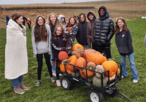 A group of people with a wagon full of pumpkins at Big Springs Farm Pumkpins and Corn Maze