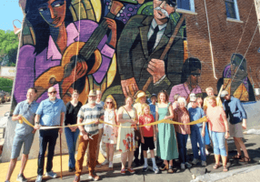 A group of people doing a ribbon cutting for a mural in Lanesboro, MN