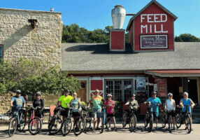 A group of bikers posing in front of Stone Mill Hotel & Suites.